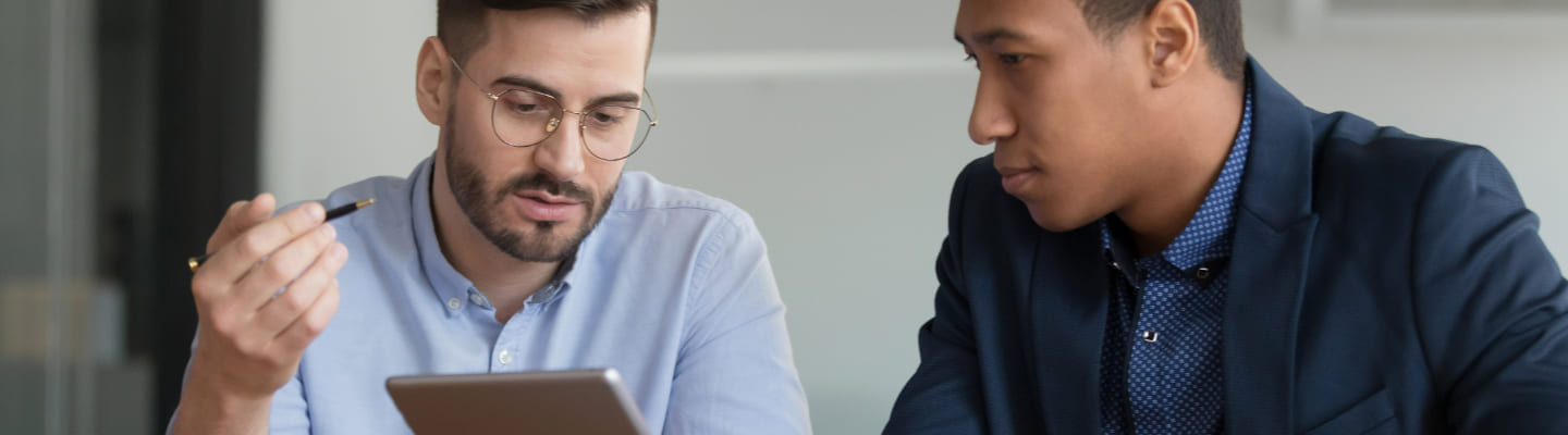 Two people talking and holding a tablet to illustrate training for businesses and enterprises